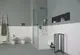 Moderne Dusche mit gläserner Abtrennung, weiße Fliesen bis zur Mitte der Wand, minimalistischer Stauraum und Sanitäranlagen, Raumgestaltung von Ideal Standard.